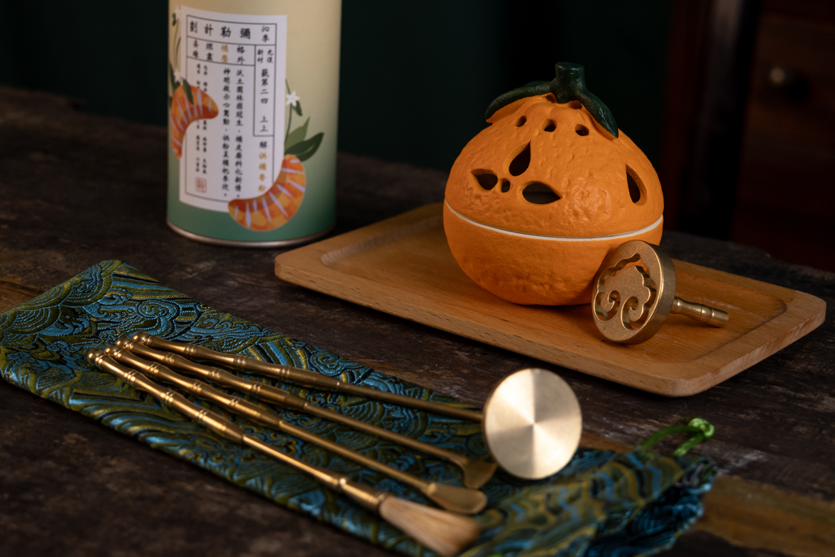 A ceramic pumpkin shaped candle holder with a book in the backgroundDescription automatically generated